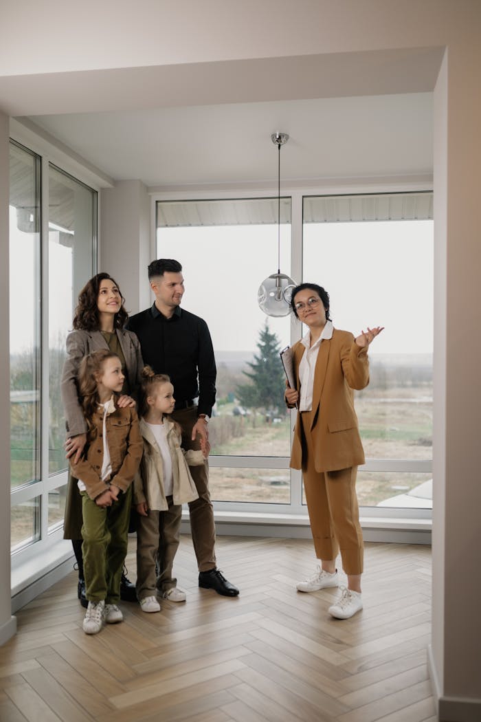 Family touring a new home guided by a real estate agent in a bright room.